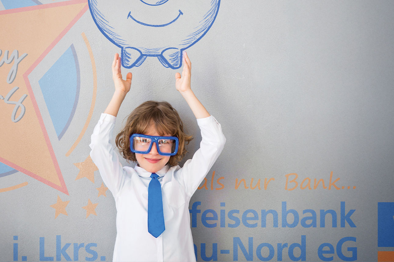 Kind hält Zeichnung eines Sparschweins vor Hintergrund mit Geldscheinen und „vrMoneyMakers!“-Schriftzug
