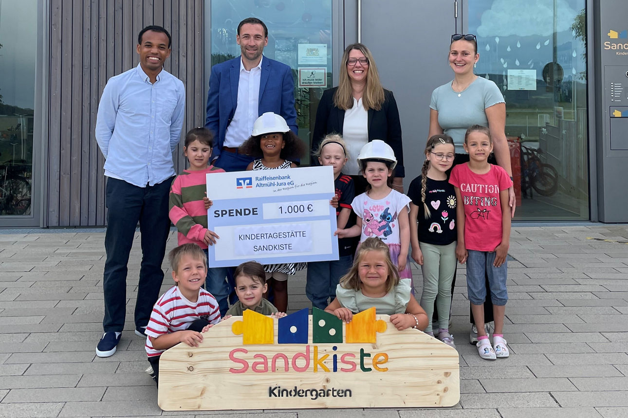 Vertreter der Raiffeisenbank Altmühl-Jura eG überreichen dem Kindergarten „Sandkiste“ eine Spende in Höhe von 1.000 Euro.