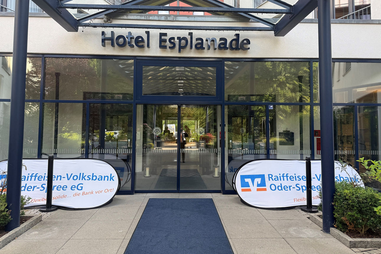 Hoteleingang mit zwei weißen Werbebannern der Raiffeisen-Volksbank Oder-Spree eG links und rechts neben der Tür