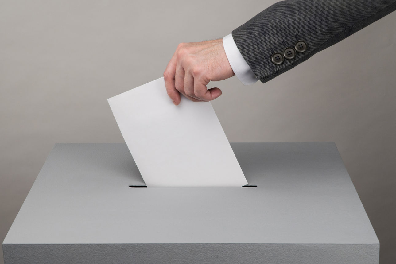 Hand wirft Wahlzettel in Wahlurne