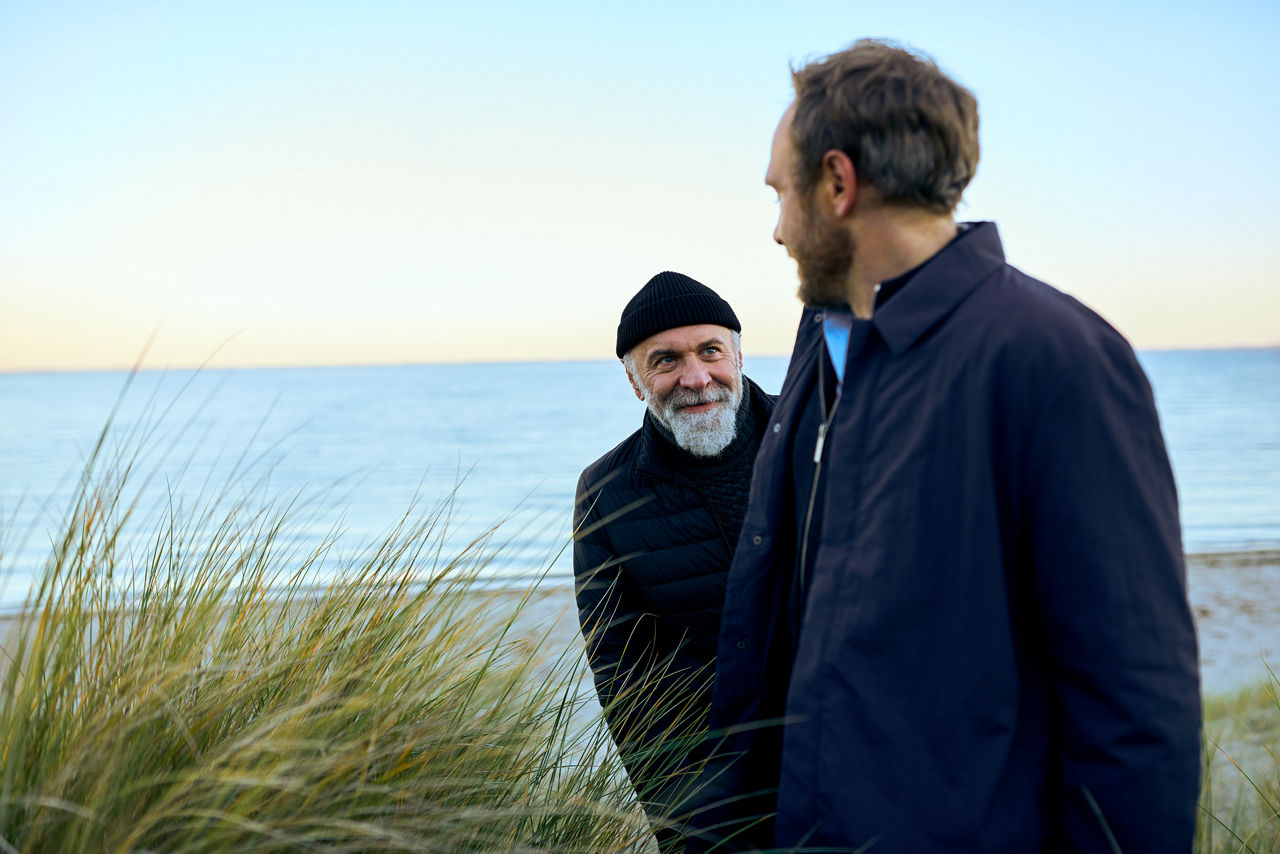 Zwei Männer stehen am Meer und schauen sich an