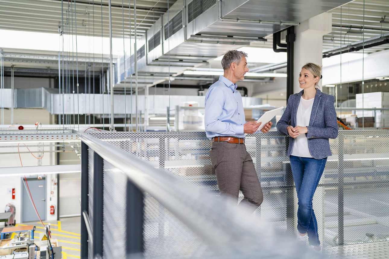 Ein Mann und eine Frau stehen an einem Geländer und besprechen etwas