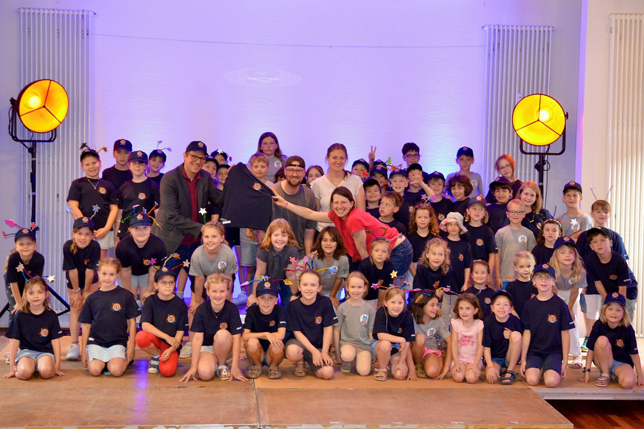 Gruppenfoto der talentierten Kinder und Erwachsenen vom Chorhaus Dormagen, die gemeinsam lächelnd auf der Bühne stehen.