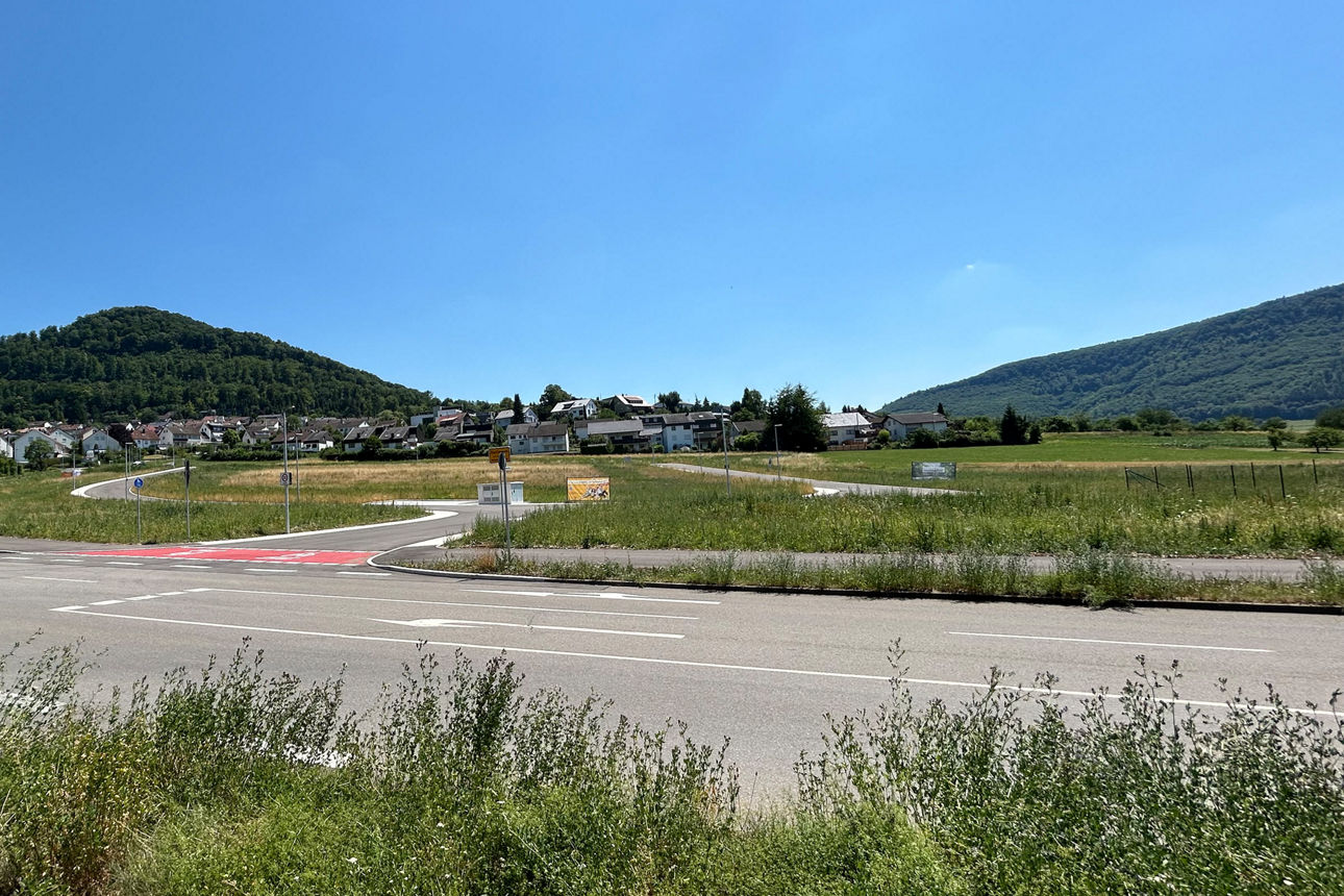 Eine Straße, daneben freies, bebaubares Feld.