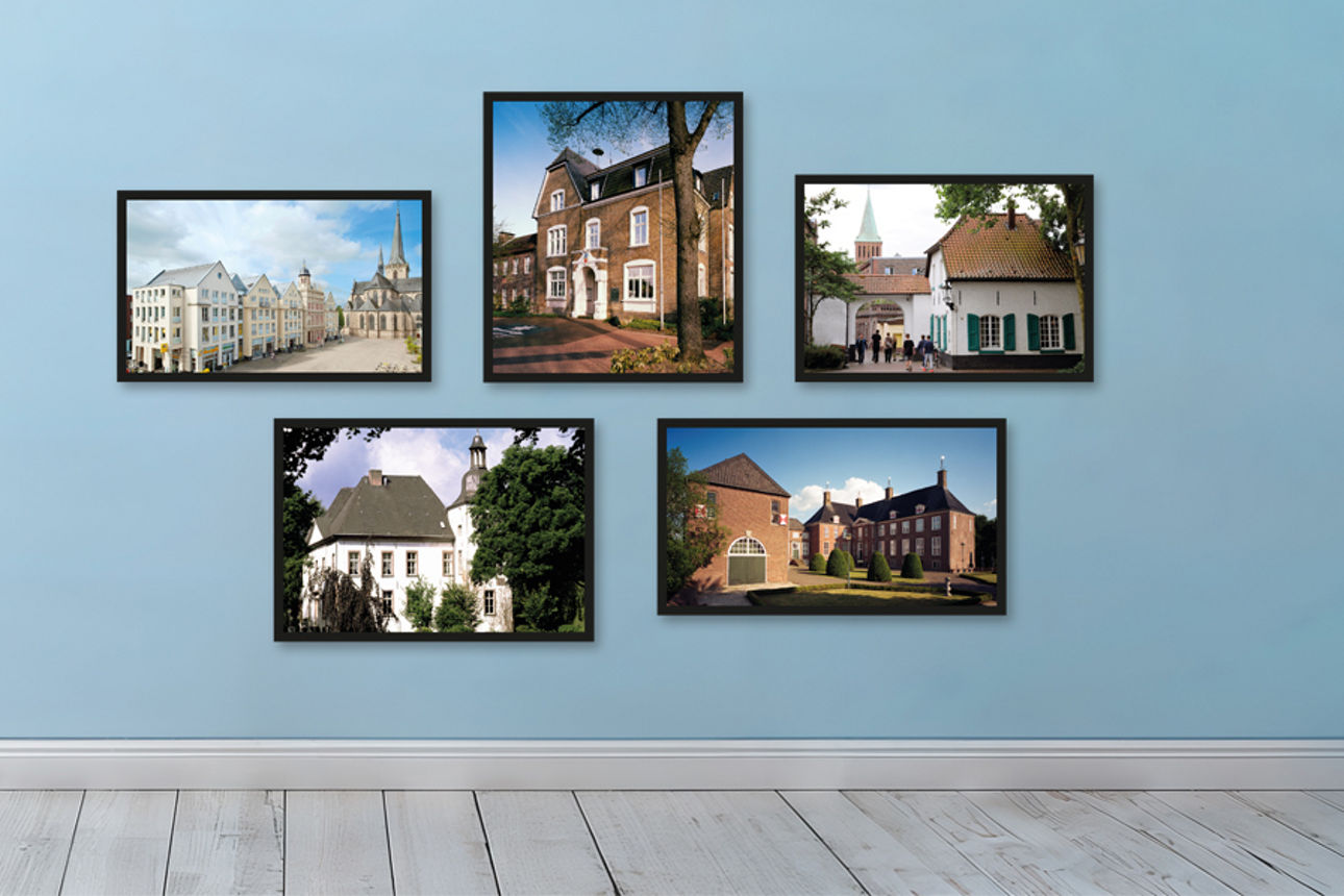 Regionale Bilder aus Dinslaken, Hamminkeln, Hünxe, Voerde und Wesel hängen in schwarzen Bilderrahmen auf einer blauen Wand. Auf der Wand ist noch der Schriftzug WIR für unsere Heimat zu lesen.