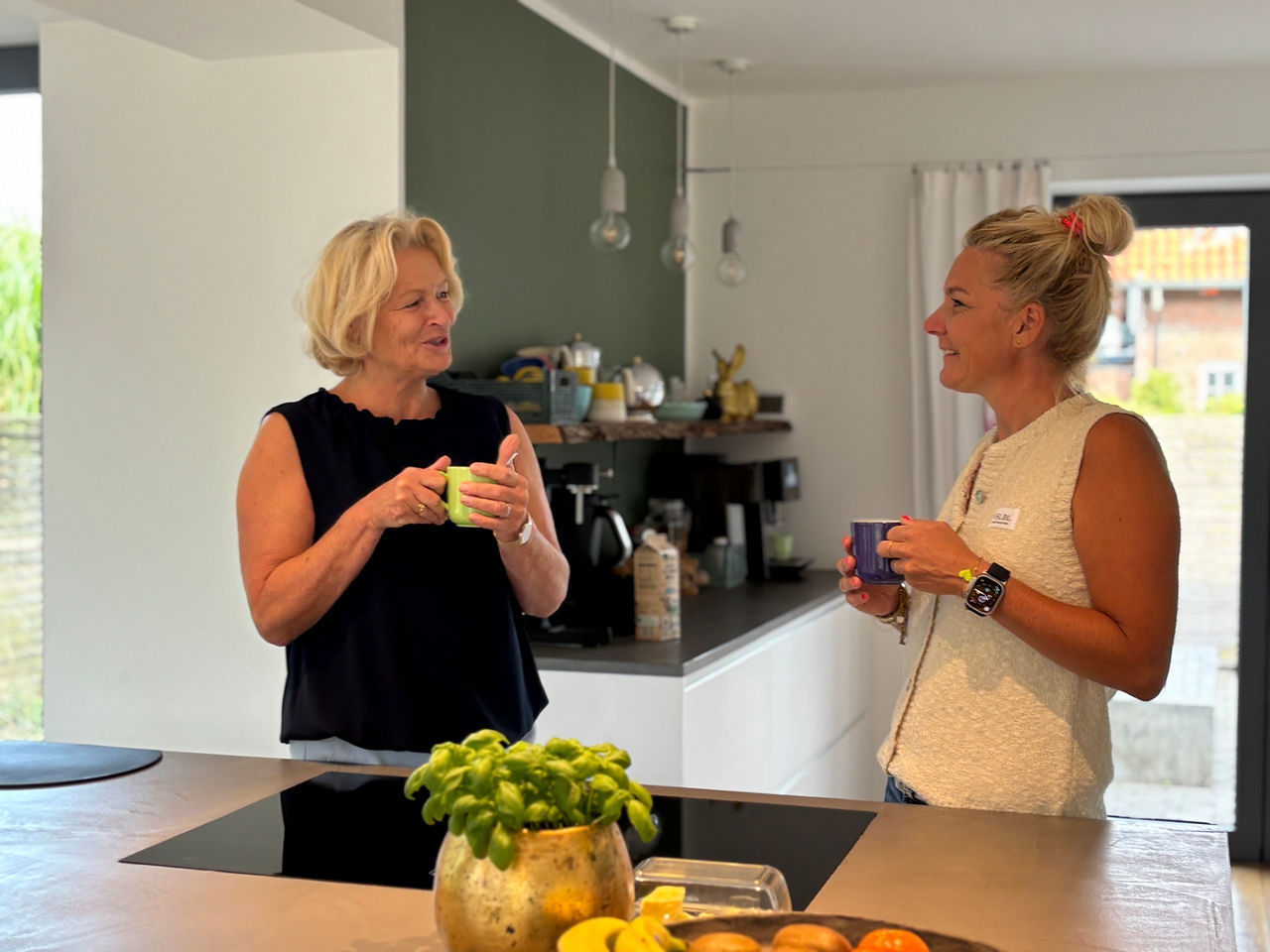 Beraterin und Kundin stehen in der Küche mit Kaffee