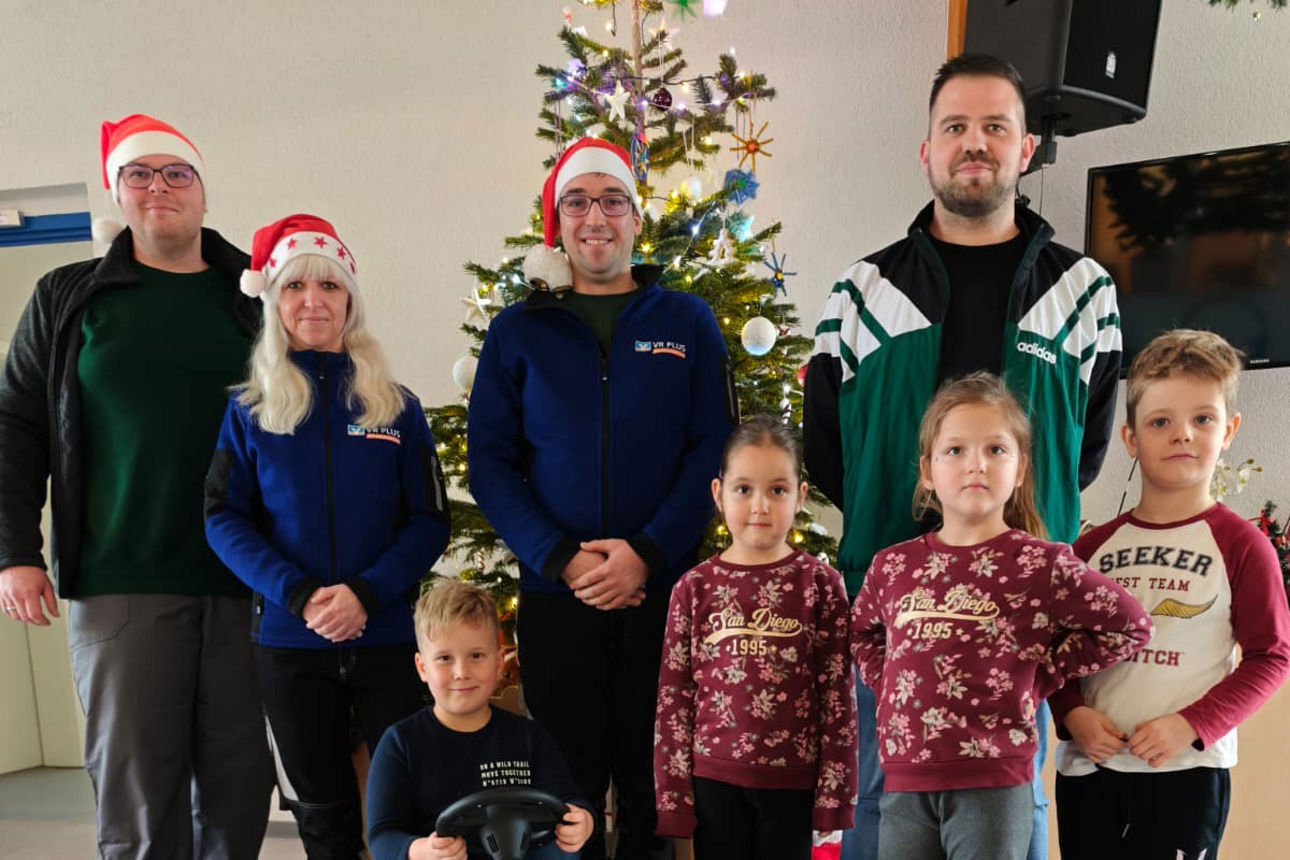Gruppe von vier Erwachsenen und vier Kindern stehen vor einem Weihnachtsbaum und einem Gokart.