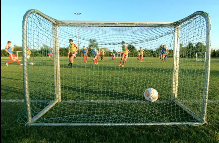 Zwei Mannschaften spielen Fußball vor einem Fußballtor