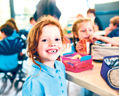 Smiling school students in uniform missing a tooth with a healthy sandwich for lunch