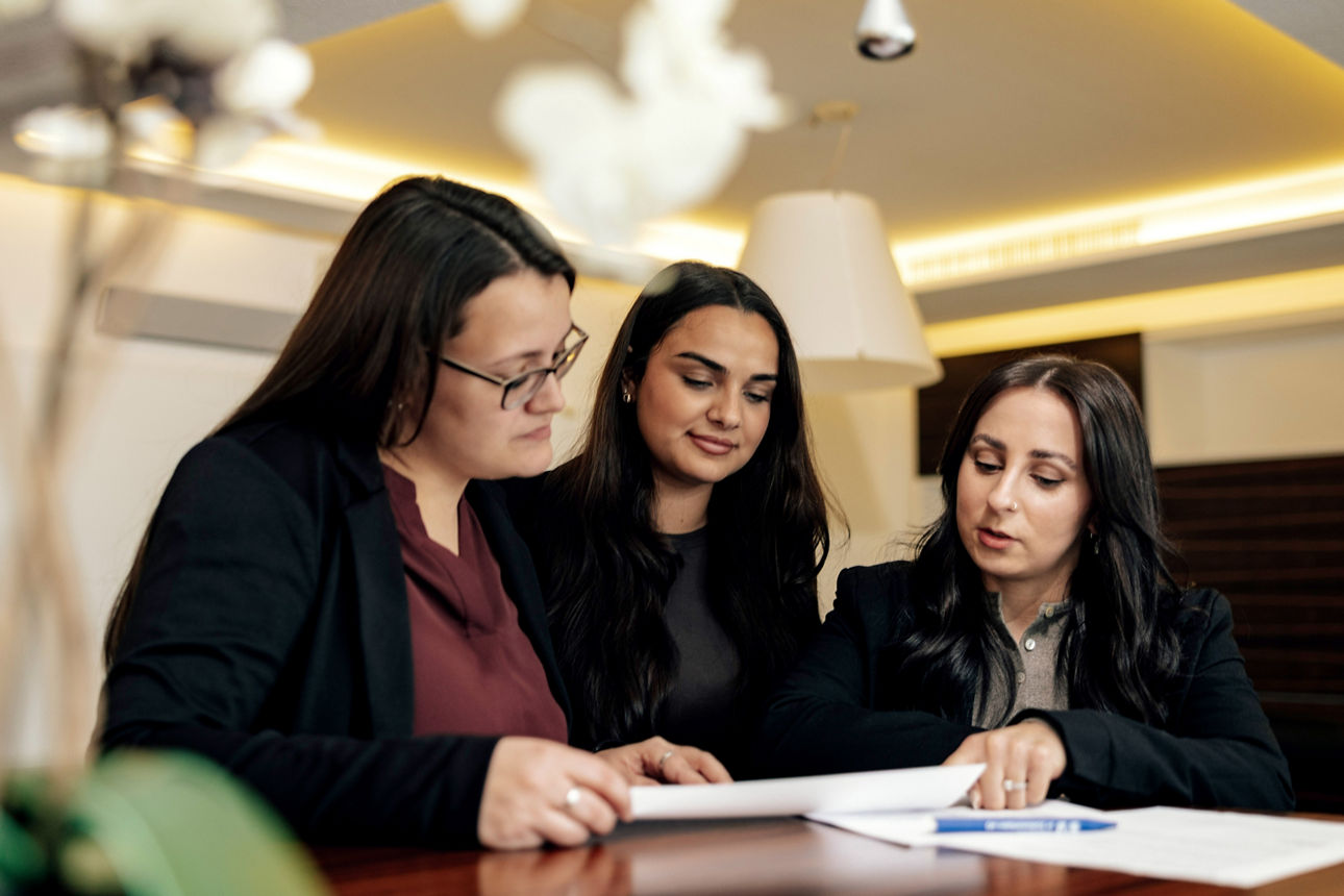 Drei Mitarbeiterinnen stehen zusammen am Tisch