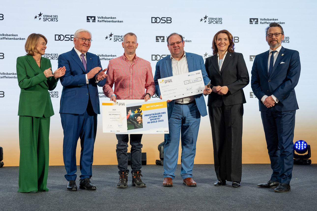 Gruppe auf Bühne bei Spendenübergabe mit Scheck und Urkunde, gemeinsames Foto