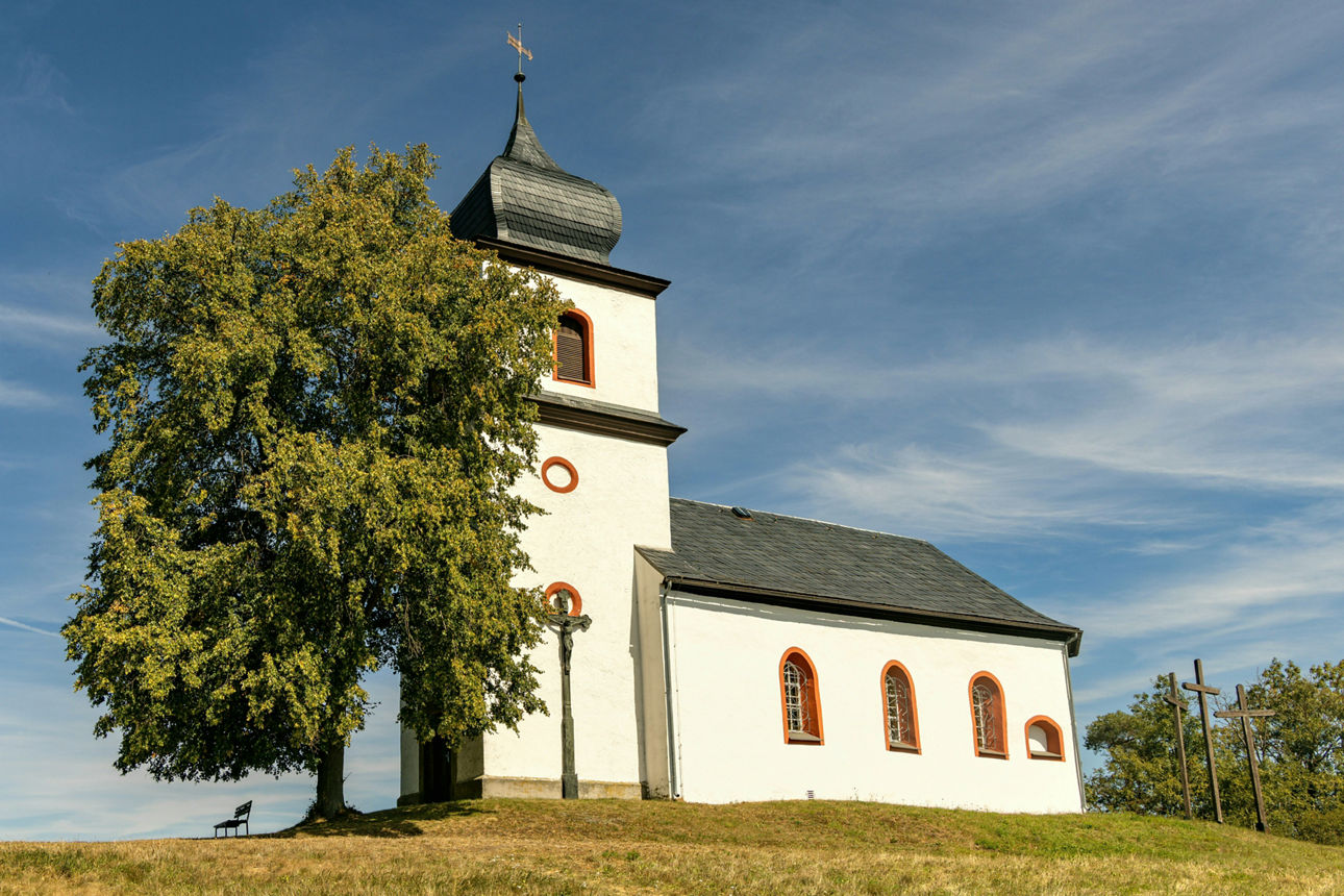 Kirche auf Hügel neben Baum