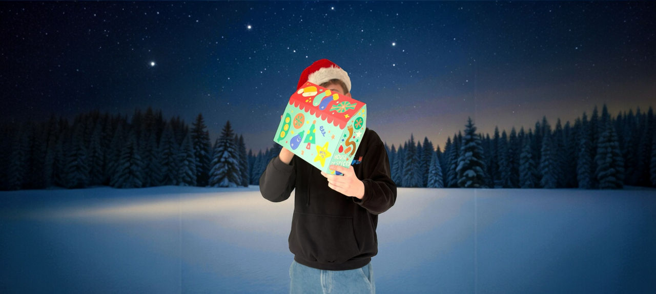 Ein Junger Mann mit Weihnachtsmütze hält einen Advendtskalender in die Kamera