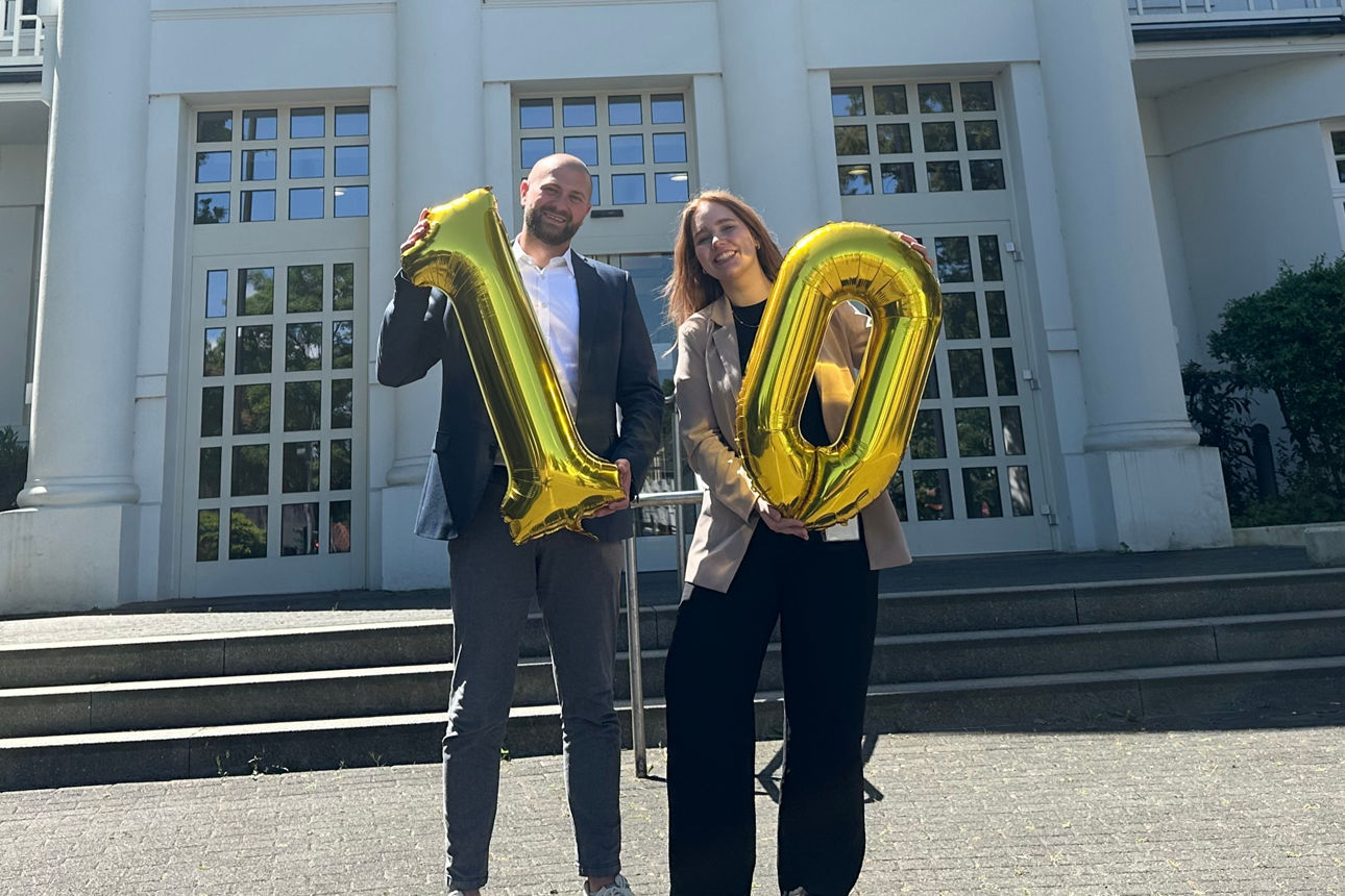 Ein Mann mit einem Luftballon mit der Zahl 1 und eine Frau mit einem Luftballon mit der Zahl 0