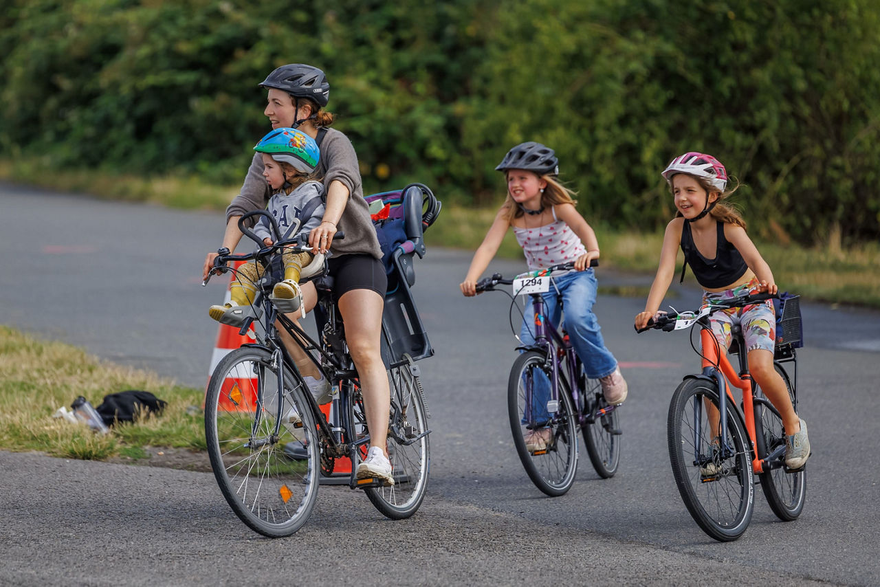 Mutter und ihre drei Kinder fahren Rad 