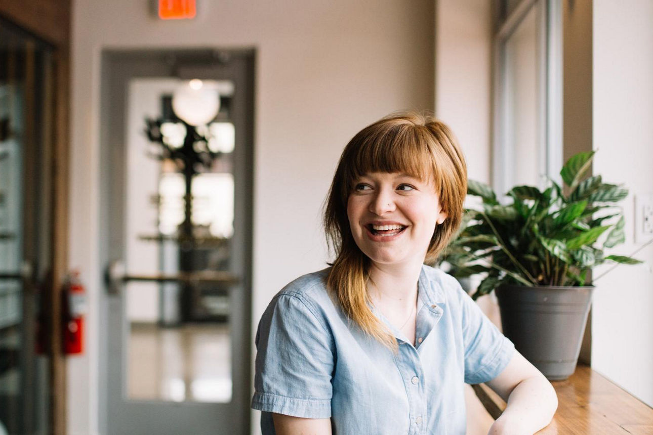 Lachende junge Frau am Tisch sitzend blickt nach links