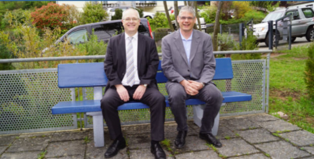 Zwei Menschen sitzen auf einer blauen Bank