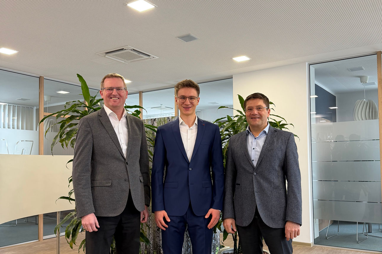 Drei Männer lächeln in die Kamera.