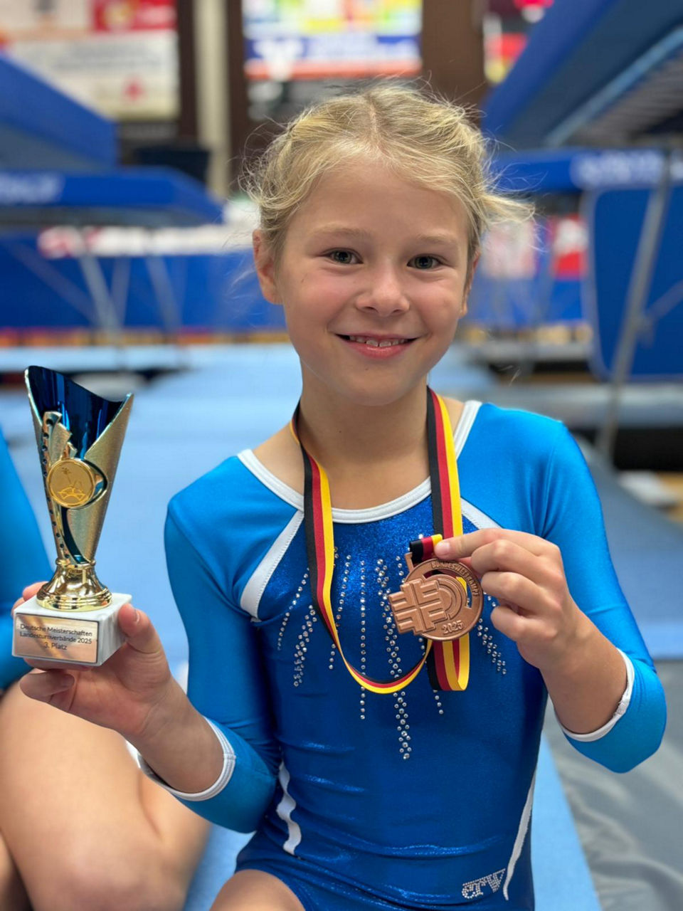 Ein junges Mädchen hält einen Pokal und eine Medaille in der Hand