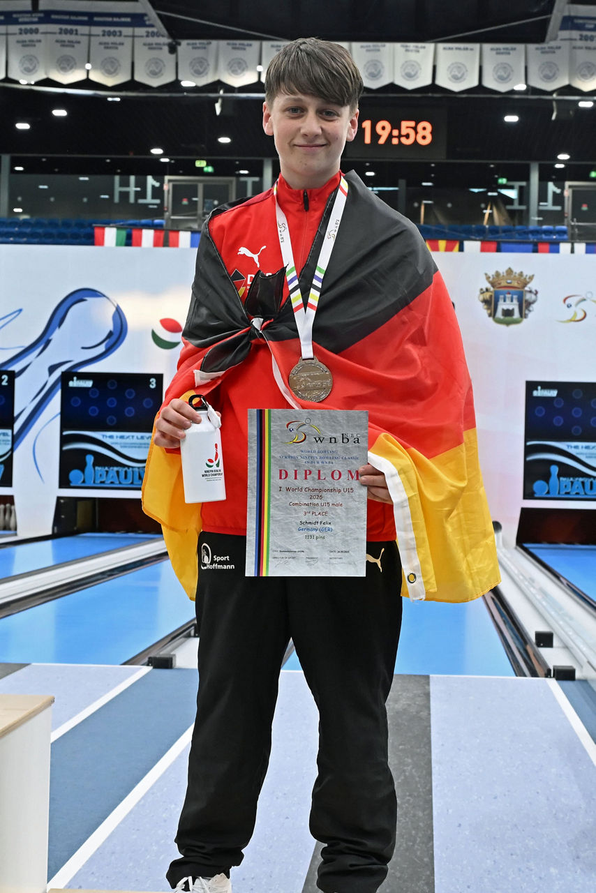 Ein Junge steht auf einen Siegerpodest und hält einen Pokal und eine Urkunden in der Hand