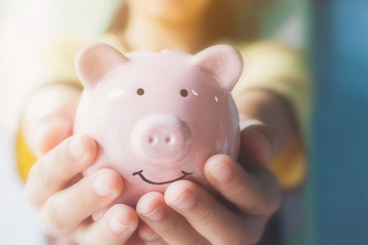 Female hand holding piggy bank. Save money and financial investment