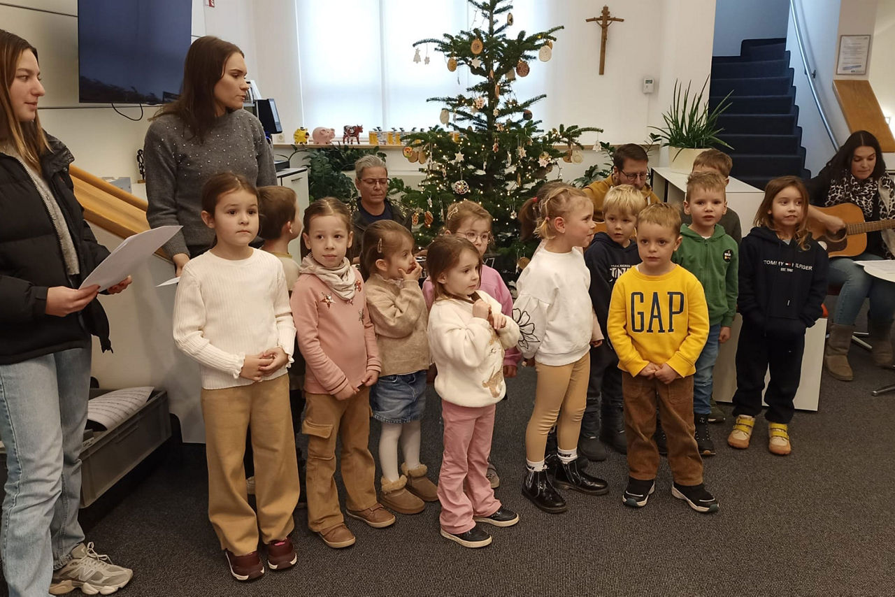 Gruppe von Kindergartenkindern vor dem geschmückten Weihnachtsbaum der Hauptstelle der Raiffeisenbank Westhausen eG