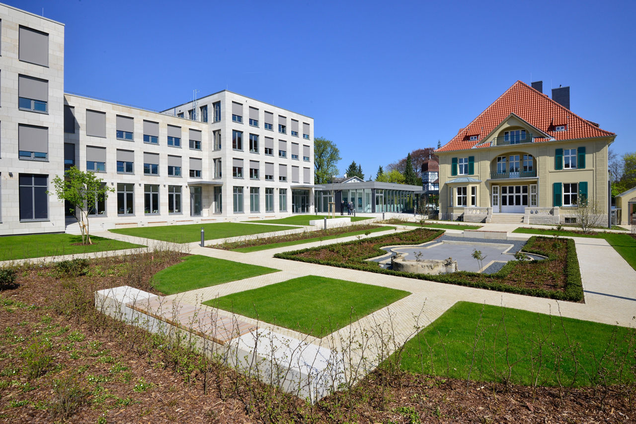 Ein Gebäude, umgeben von einem üppigen Garten und hohen Bäumen