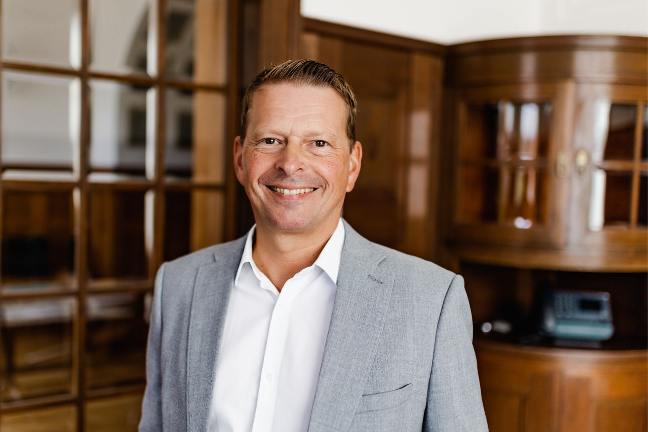 Porträt eines Mannes im hellen Sakko in elegantem Innenraum mit Holzvertäfelung