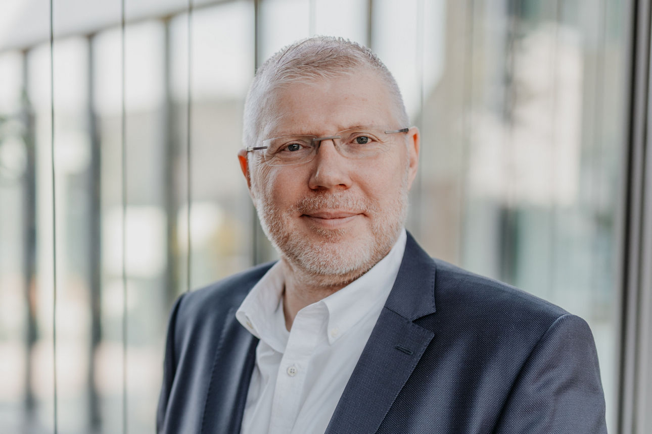 Porträt eines Mannes im Anzug vor moderner Glasfassade, Businessaufnahme im Außenbereich