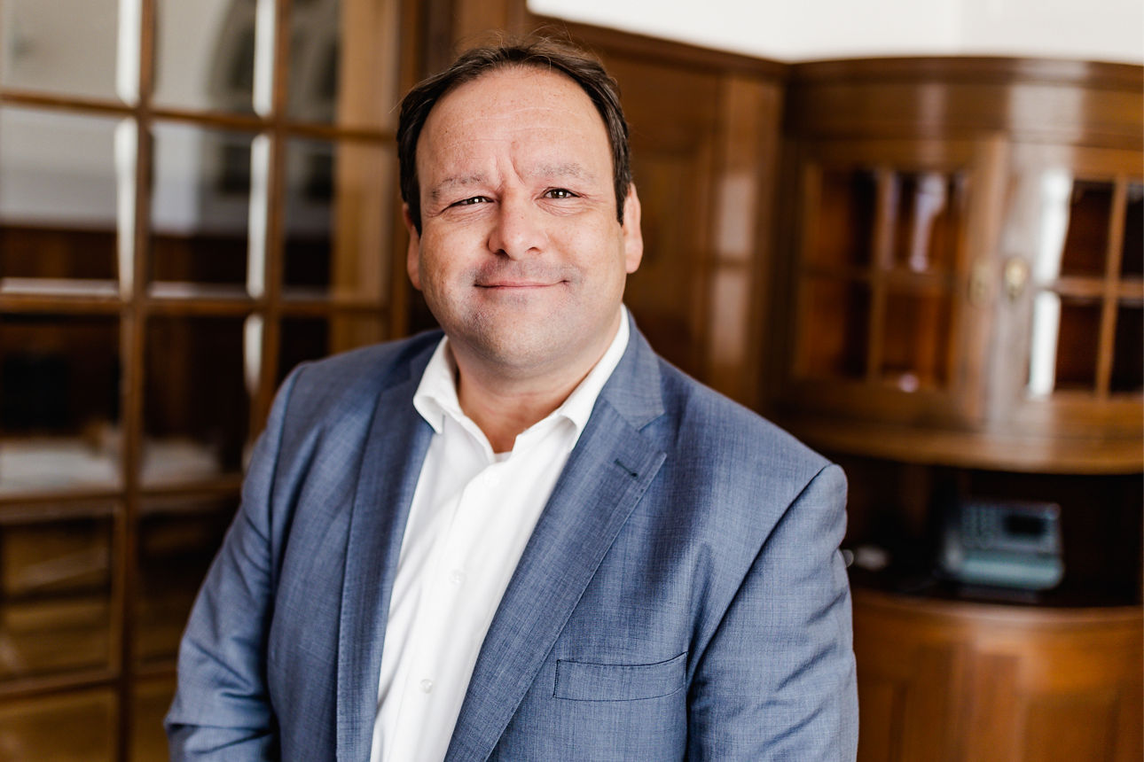 Porträt eines Mannes im blauen Sakko in stilvollem Innenraum mit Holzvertäfelung