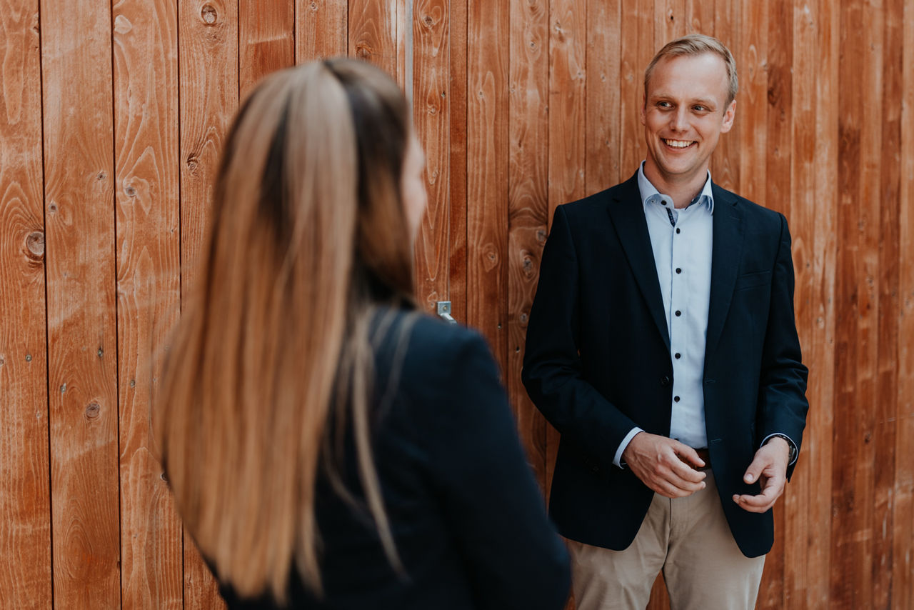 Zwei Personen in Business Kleidung lächeln und sprechen