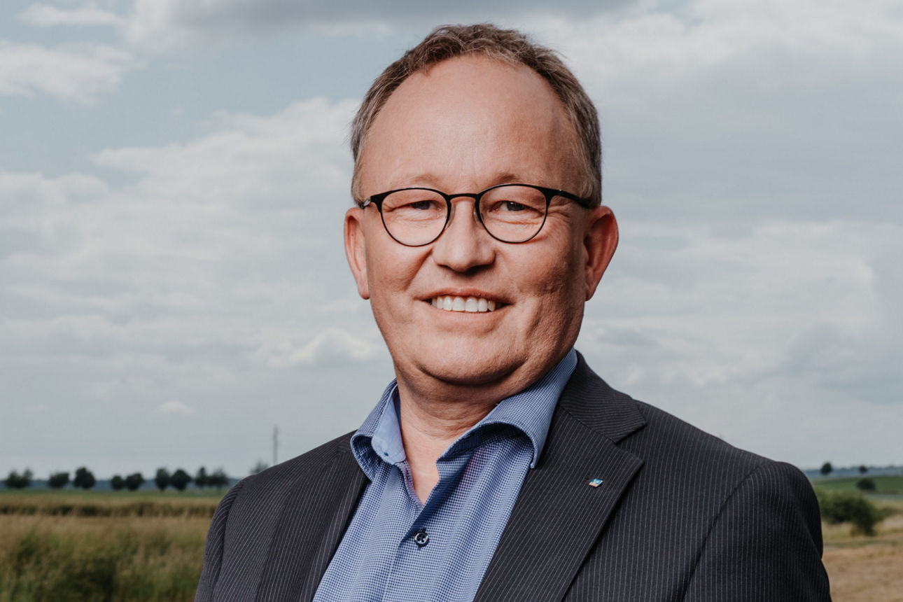 Berater Pultke steht in Business Kleidung auf einem Feld.