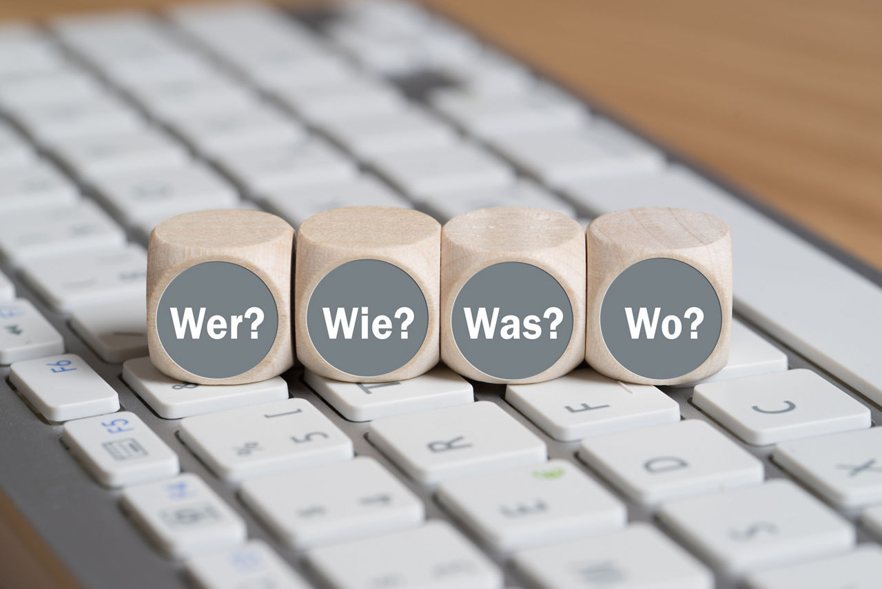cubes with the words "who, how, what, when" in German on a keyboard