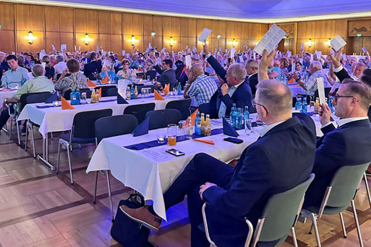 Mitglieder heben Stimmkärtchen bei der Mitgliederversammlung 2025