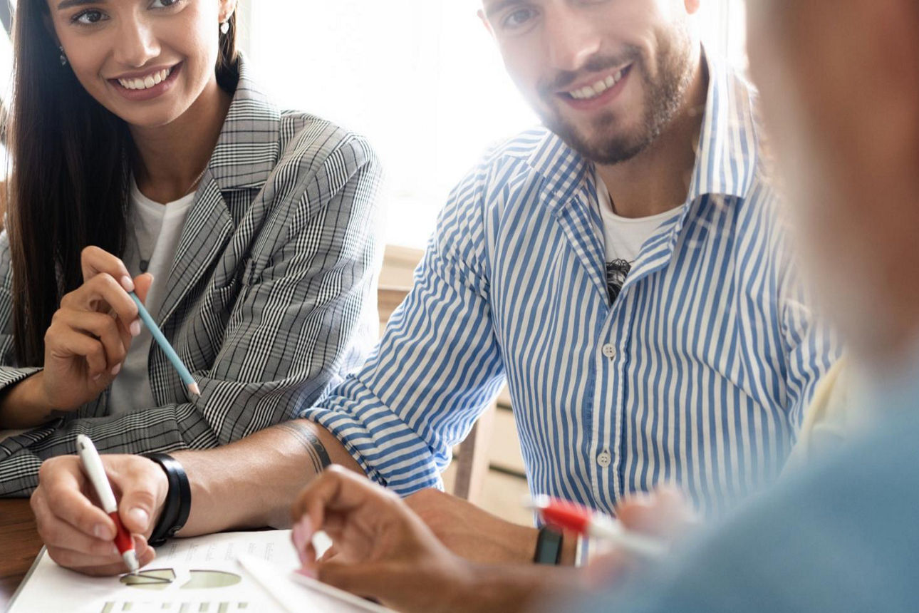 Drei Menschen am Tisch im Beratungsgespräch mit Dokumenten