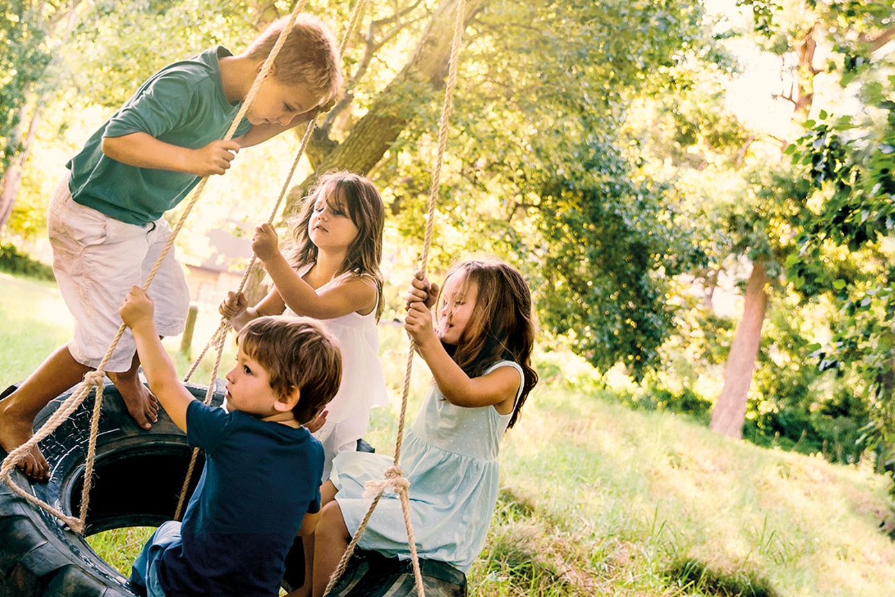 4 Kinder spielen auf einer Schaukel