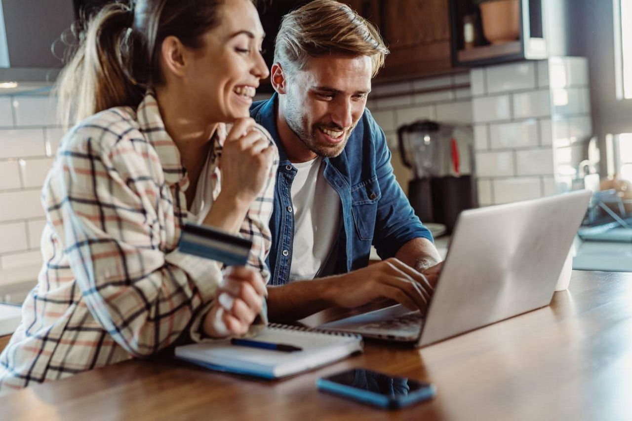 Paar sitzt vor Laptop und checkt gemeinsame Finanzen