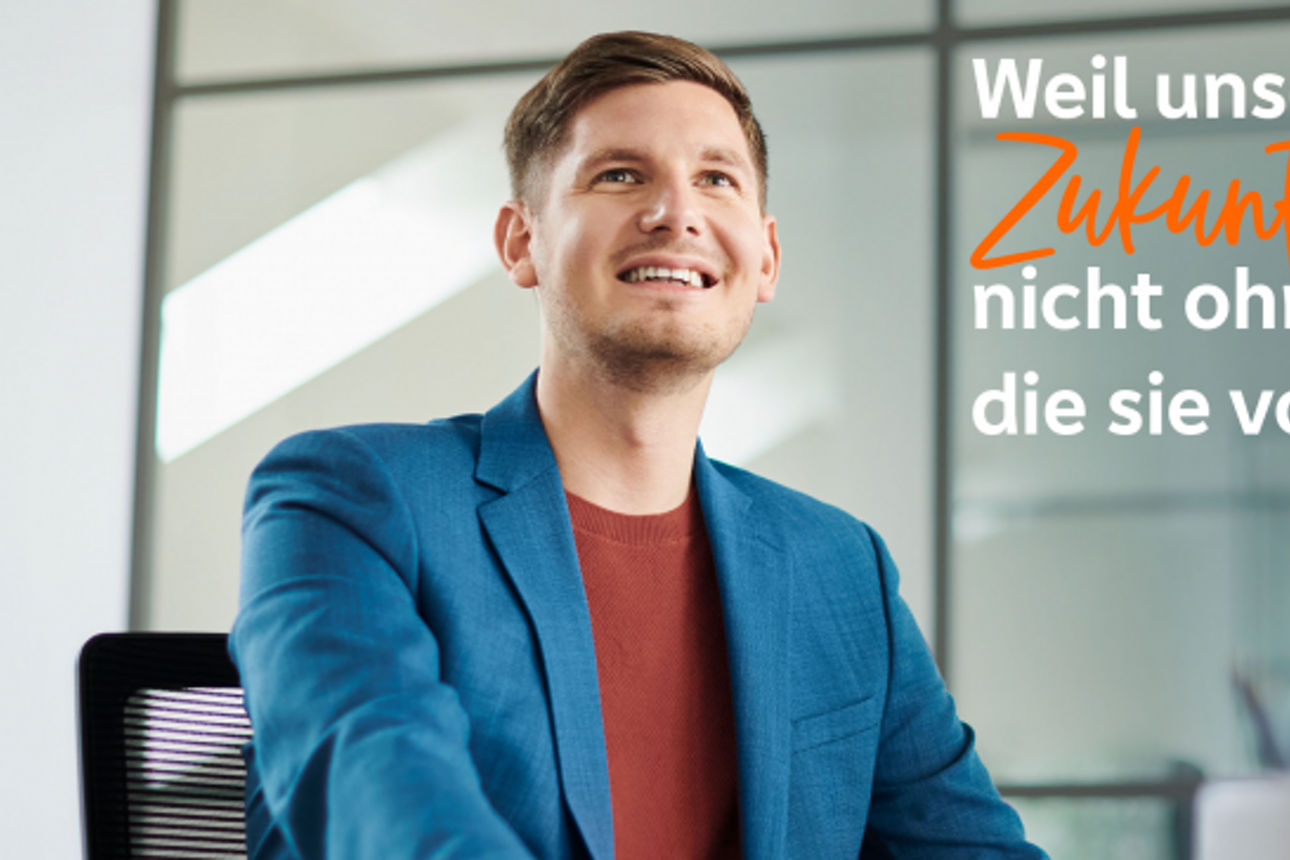 Ein Mann sitzt an einem Schreibtisch und konzentriert sich auf einen Computerbildschirm in einer gut beleuchteten Büroumgebun