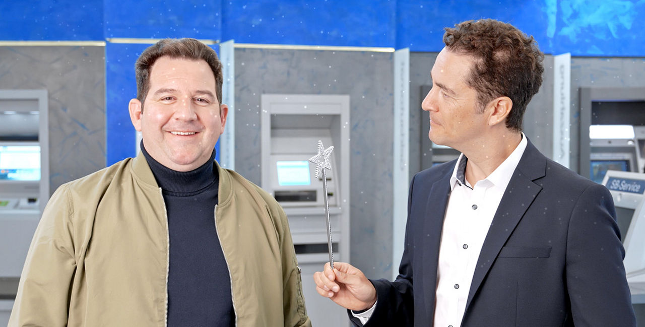 Bänker steht mit Kunde vor den Automaten in der Hauptstelle Öhringen