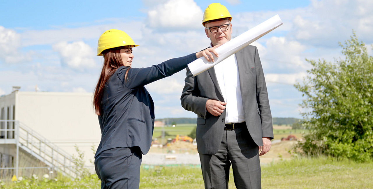Beraterin steht mit einem Kunde auf der Baustelle