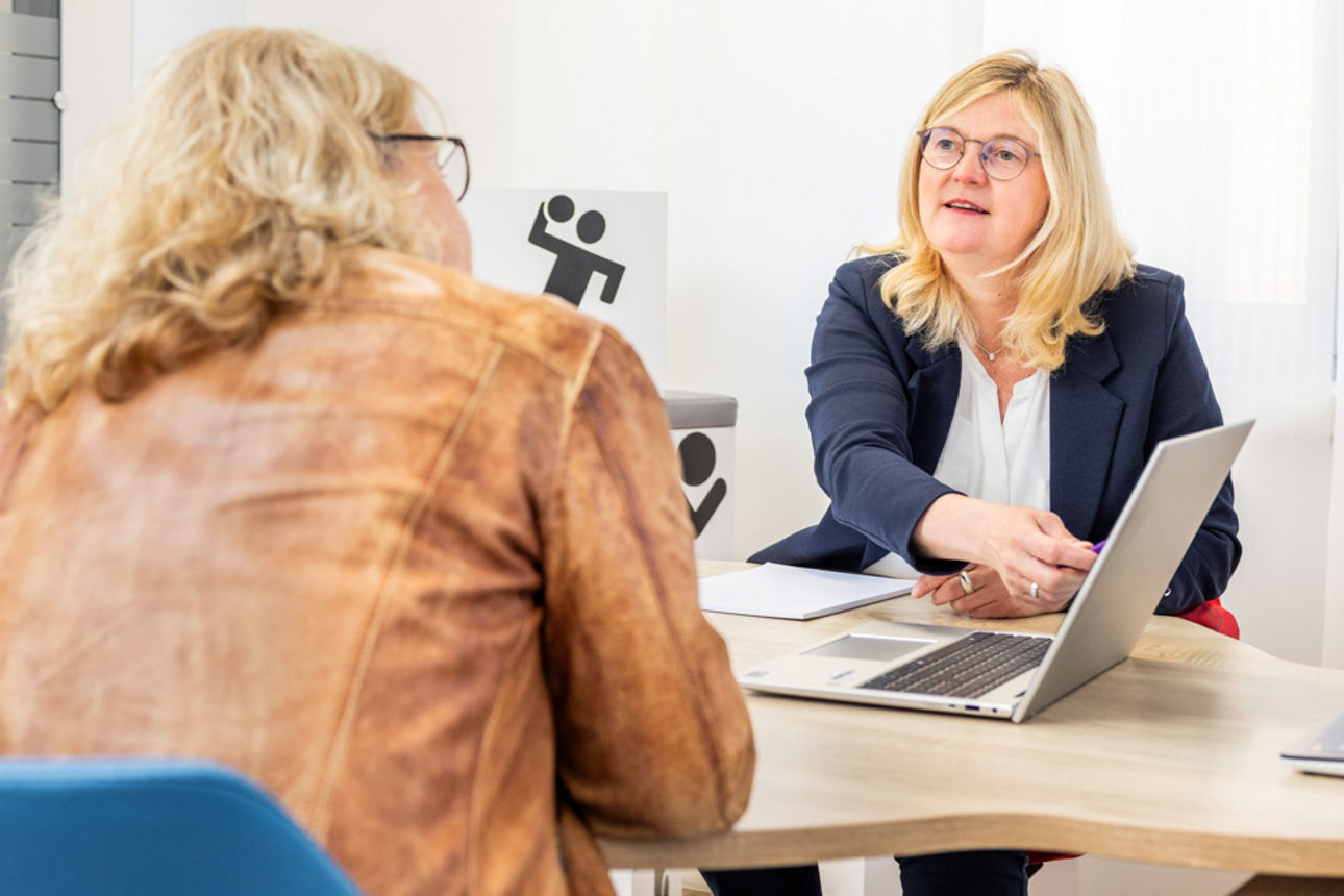 Eine Kundenberaterin und eine Kundin sitzen am Beratungstisch