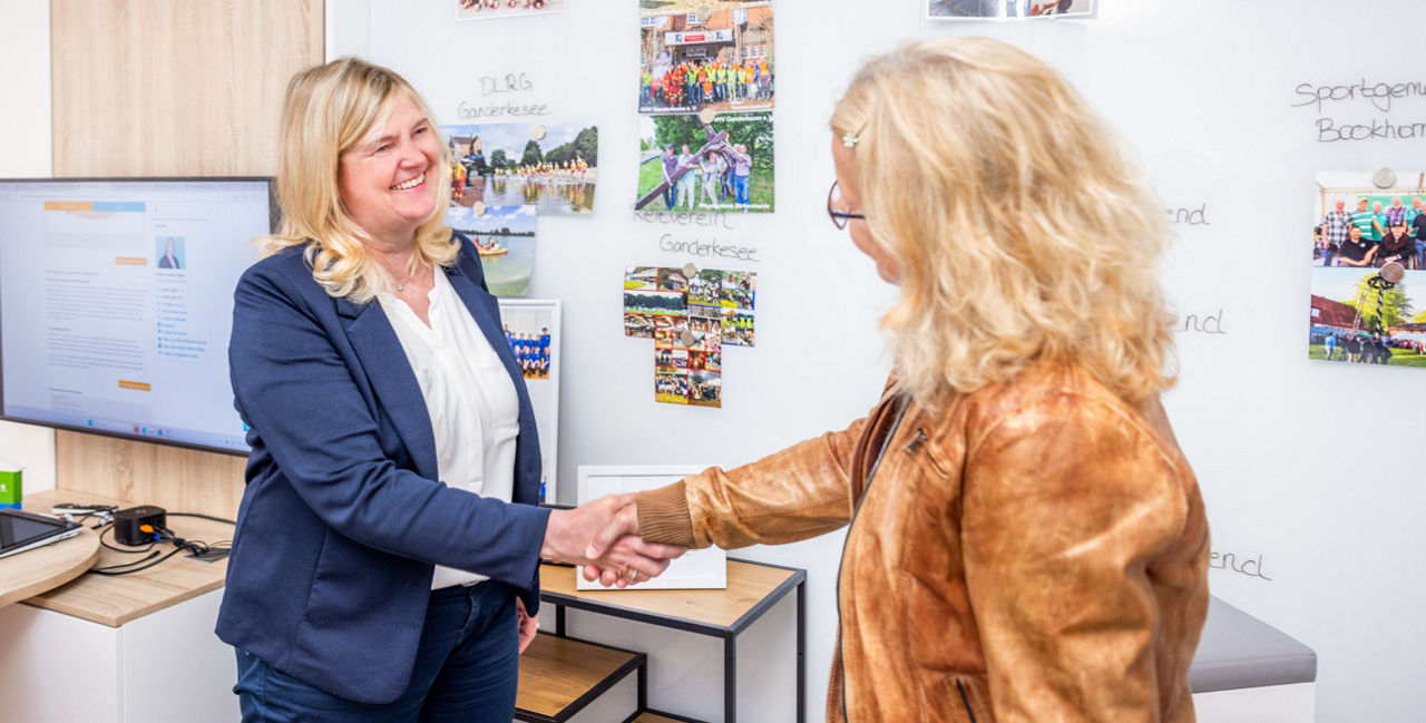 Zwei Frauen geben sich im Beratungszimmer die Hände
