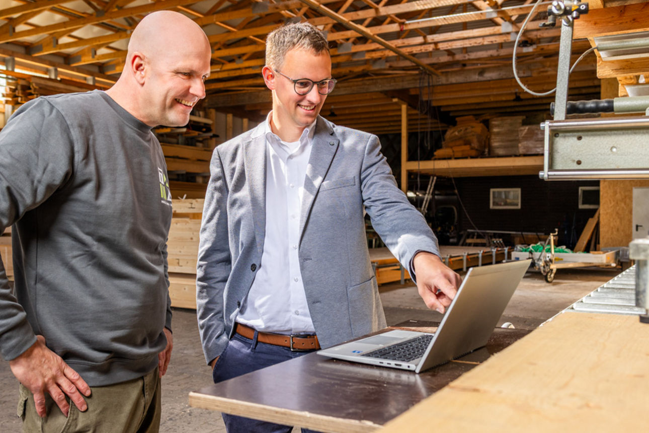 Zwei Männer stehen in einer Werkstatt vor einem Laptop