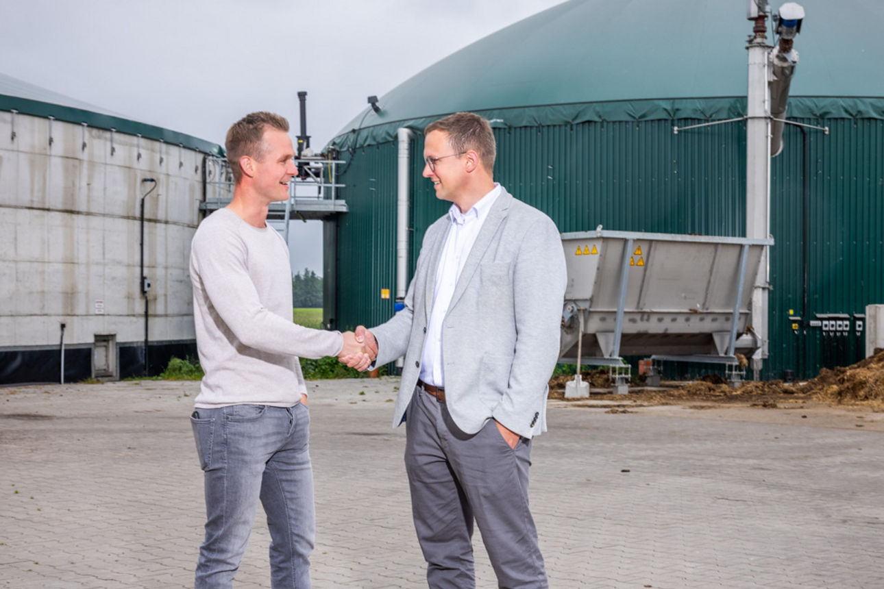 Ein Geschäftsführer eines Unternehmens und ein Bankberater geben sich auf einem Hof die Hände
