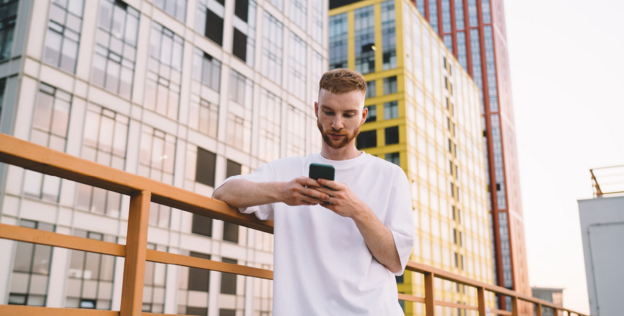 Junger Mann mit Handy vor Hochhäusern