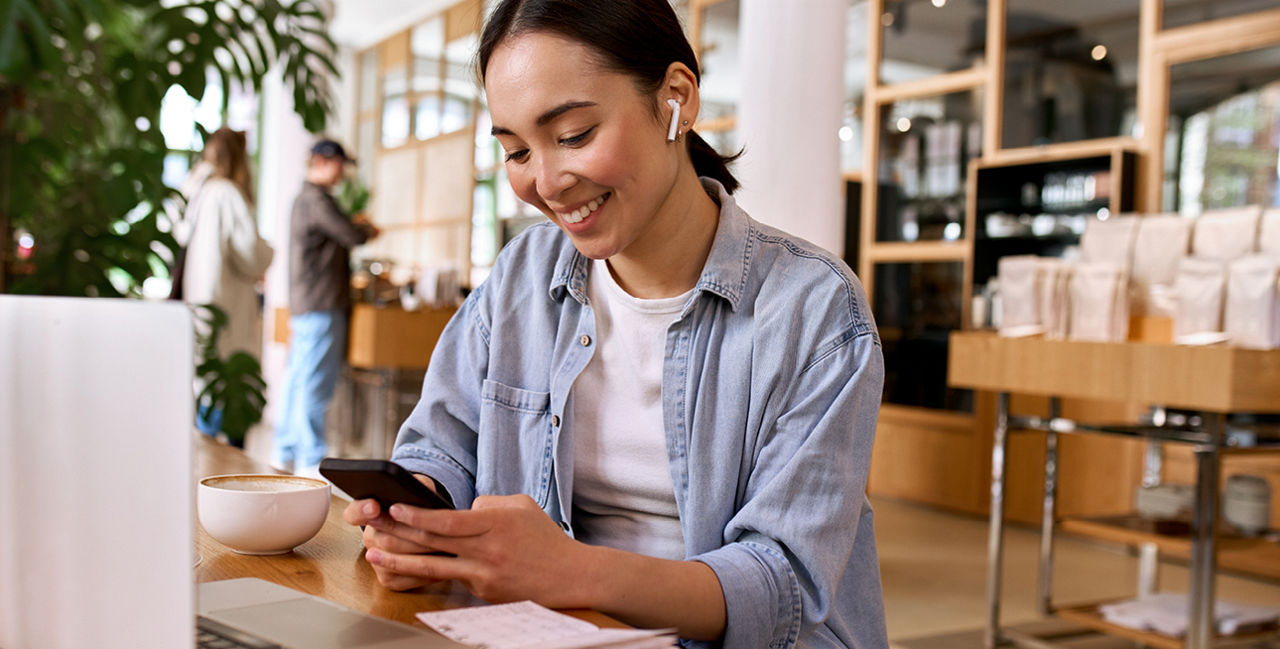 Junge Frau mit Handy vor Laptop