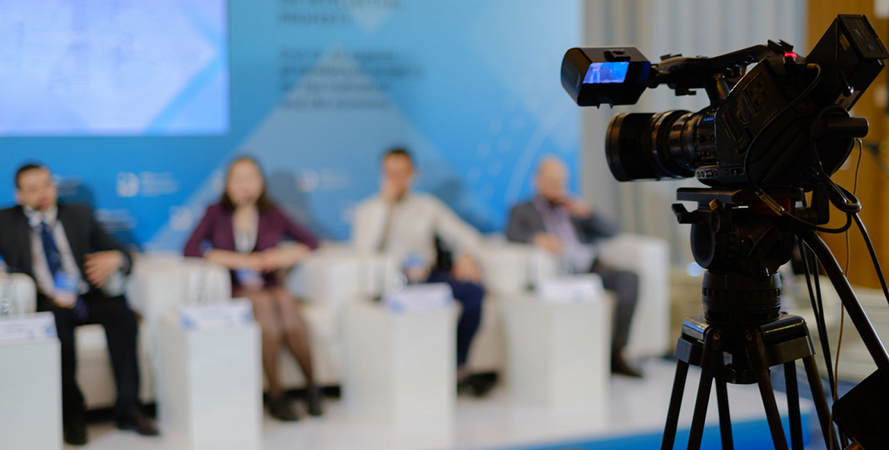 Videokamera nimmt vier Personen auf, die im Hintergrund sitzen