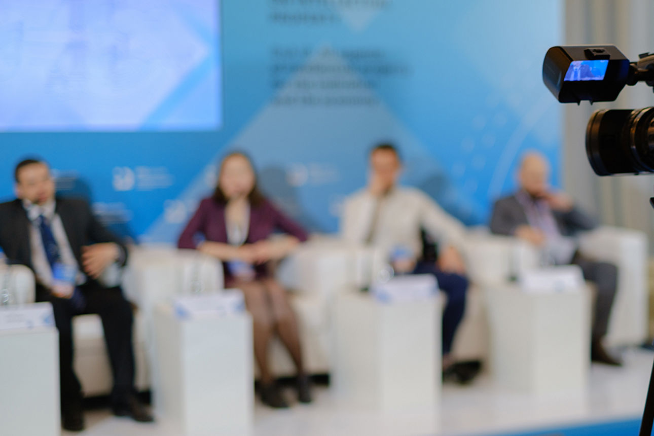 Videokamera nimmt vier Personen auf, die im Hintergrund sitzen