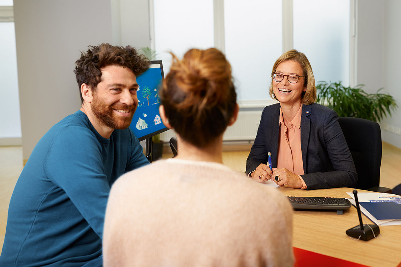 Zwei Frauen und ein Mann sitzen am Schreibtisch