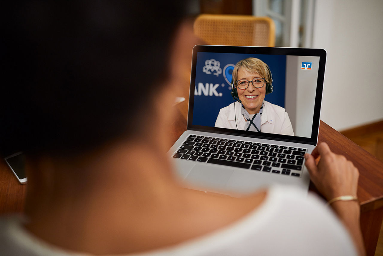 Frau hält Laptop in der Hand und nimmt an einer Videoberatung teil